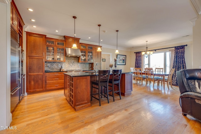 kitchen with hanging light fixtures, an island with sink, tasteful backsplash, a breakfast bar area, and a chandelier