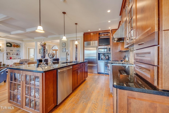 kitchen with sink, hanging light fixtures, ventilation hood, a center island with sink, and appliances with stainless steel finishes