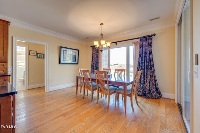 dining area with crown molding, light wood-type flooring, and a notable chandelier