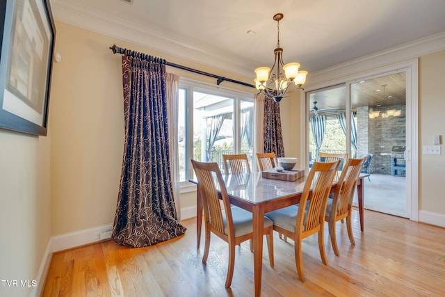 dining room with light wood-type flooring, an inviting chandelier, a wealth of natural light, and crown molding