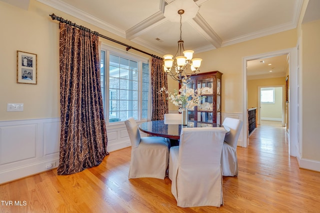 dining area with beam ceiling, light hardwood / wood-style floors, an inviting chandelier, and ornamental molding