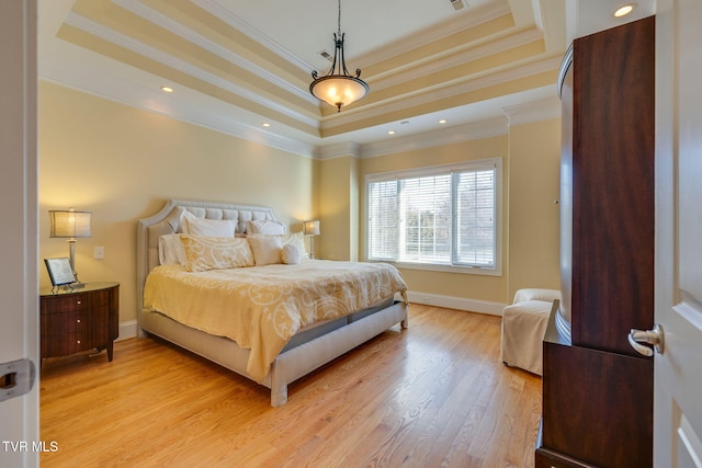 bedroom featuring a raised ceiling, light wood-type flooring, and crown molding