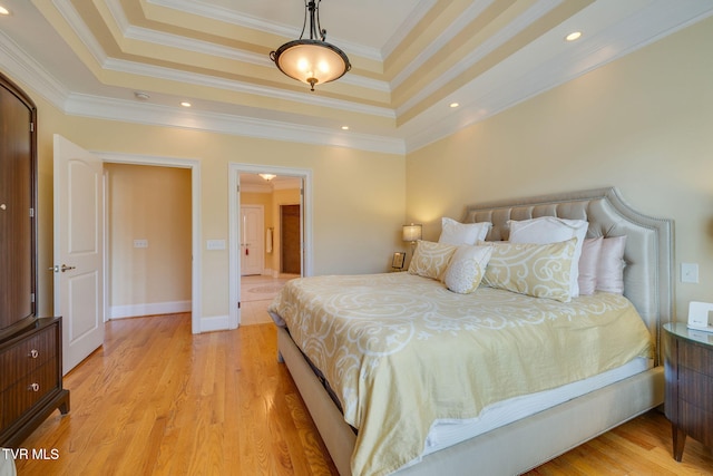 bedroom featuring a raised ceiling, crown molding, and light wood-type flooring