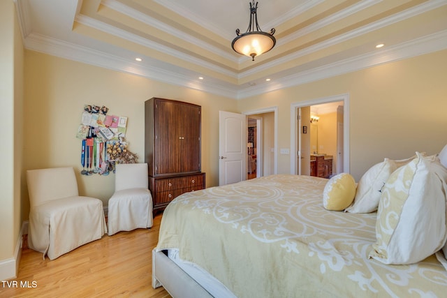 bedroom featuring a raised ceiling, ensuite bath, crown molding, and light wood-type flooring