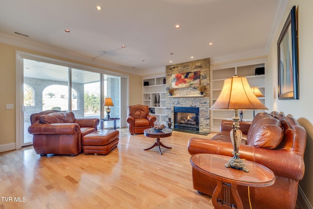 living room featuring built in shelves, light hardwood / wood-style flooring, ornamental molding, and a stone fireplace