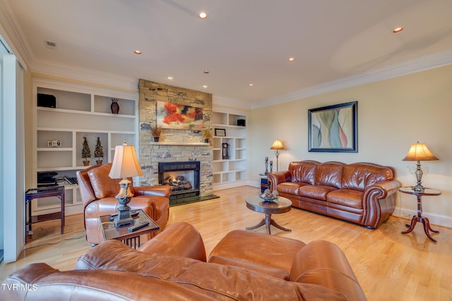 living room featuring built in shelves, light hardwood / wood-style flooring, a stone fireplace, and crown molding