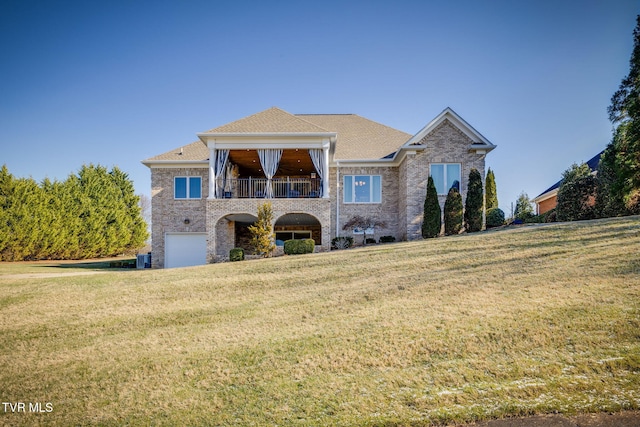 view of front of property featuring a garage, a balcony, and a front lawn