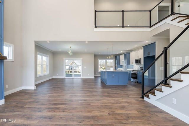 unfurnished living room with a wealth of natural light, ornamental molding, dark hardwood / wood-style floors, and sink