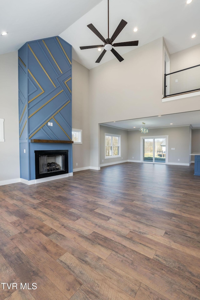 unfurnished living room with a high ceiling, ceiling fan, a fireplace, and hardwood / wood-style floors