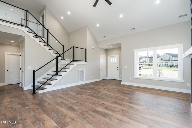 foyer entrance with ceiling fan, a towering ceiling, and hardwood / wood-style flooring