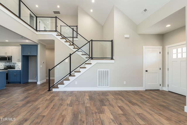 foyer entrance featuring a towering ceiling and dark hardwood / wood-style flooring