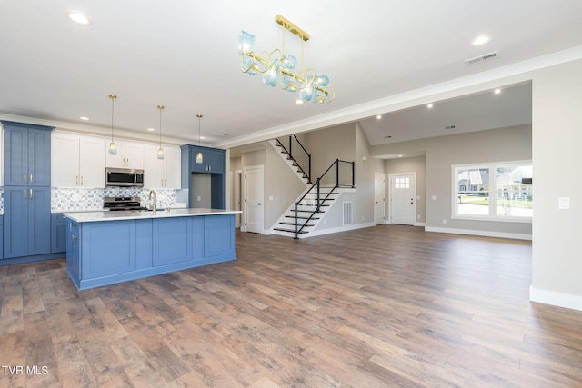 kitchen featuring white cabinetry, hanging light fixtures, a center island with sink, and stainless steel appliances