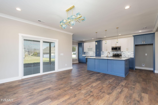 kitchen with decorative light fixtures, white cabinetry, a center island with sink, and ornamental molding