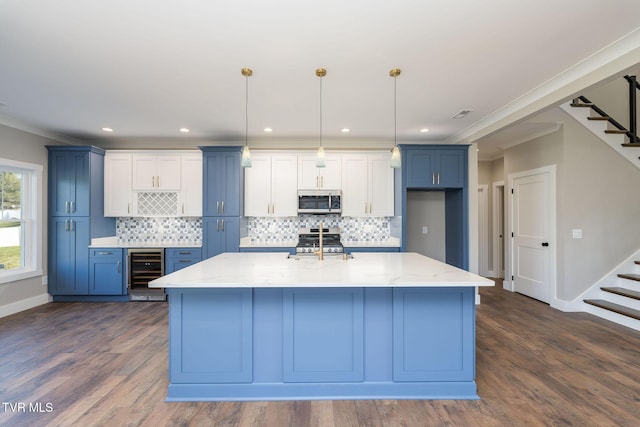 kitchen featuring wine cooler, decorative light fixtures, a kitchen island with sink, light stone countertops, and stainless steel appliances