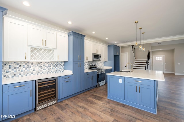 kitchen with stainless steel appliances, a kitchen island with sink, beverage cooler, hanging light fixtures, and white cabinets