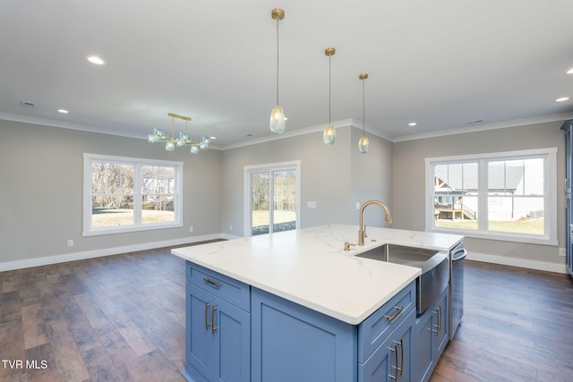 kitchen with crown molding, sink, hanging light fixtures, and an island with sink