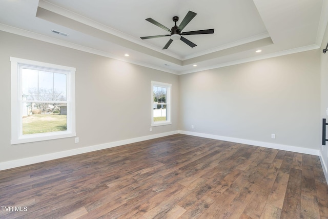 empty room with ceiling fan, dark wood-type flooring, a tray ceiling, and crown molding