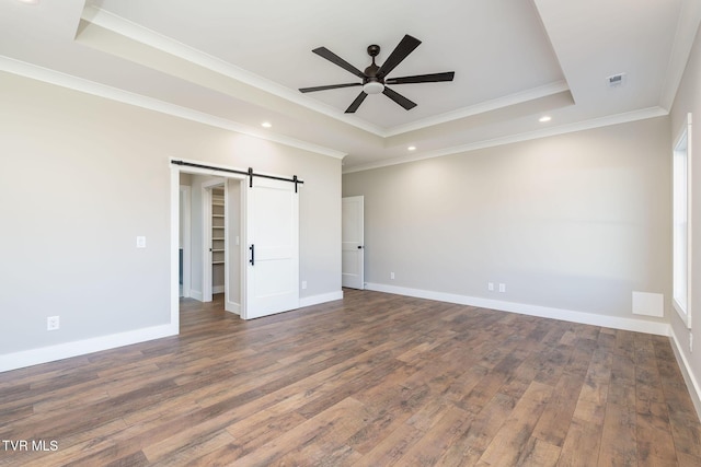 unfurnished bedroom with dark hardwood / wood-style floors, a raised ceiling, ceiling fan, crown molding, and a barn door