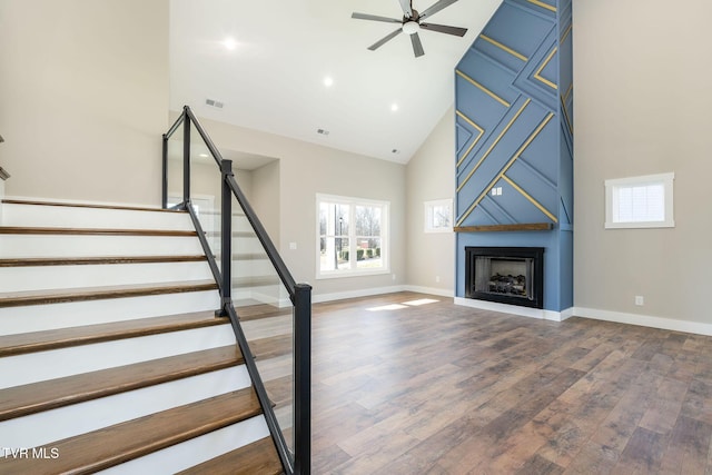 stairway featuring high vaulted ceiling, hardwood / wood-style flooring, and ceiling fan