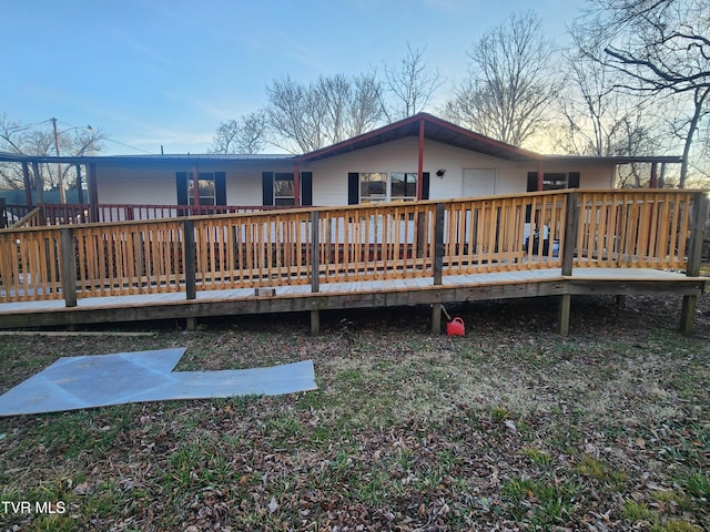 back house at dusk with a deck with water view