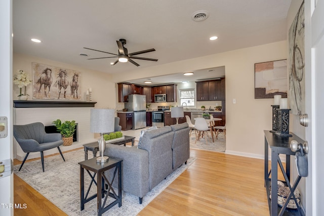 living room featuring ceiling fan, light hardwood / wood-style floors, and sink