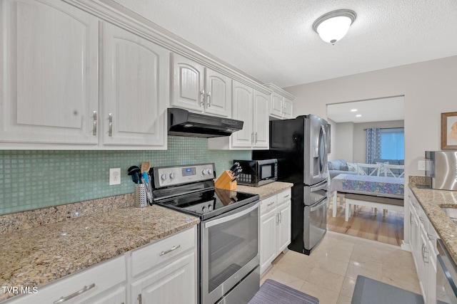 kitchen featuring backsplash, light stone countertops, light tile patterned floors, appliances with stainless steel finishes, and white cabinetry