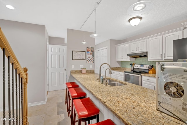 kitchen with electric range, light stone counters, white cabinetry, and sink