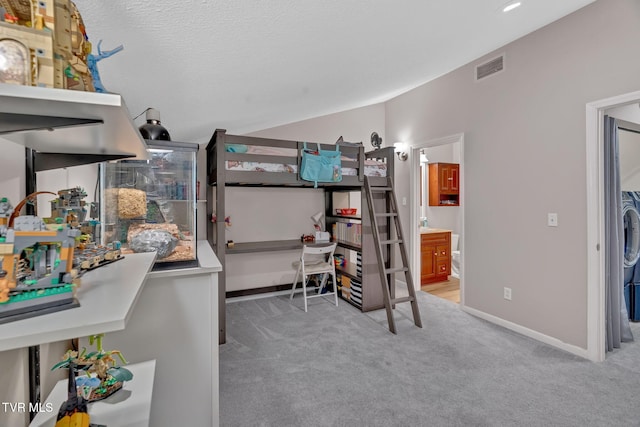 bedroom with a textured ceiling, light carpet, and ensuite bath