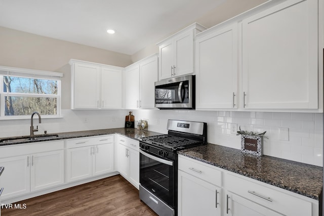 kitchen featuring dark stone counters, stainless steel appliances, sink, white cabinets, and dark hardwood / wood-style floors