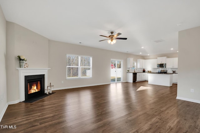 unfurnished living room featuring ceiling fan, dark hardwood / wood-style flooring, and sink