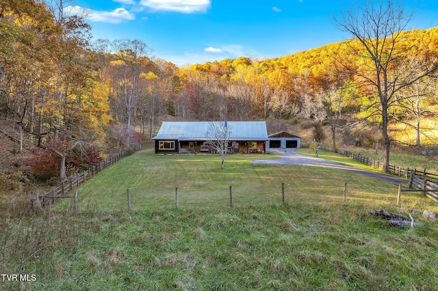 view of front of house featuring a mountain view, a rural view, an outbuilding, and a front lawn