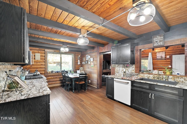 kitchen featuring dishwasher, decorative light fixtures, rustic walls, and beamed ceiling