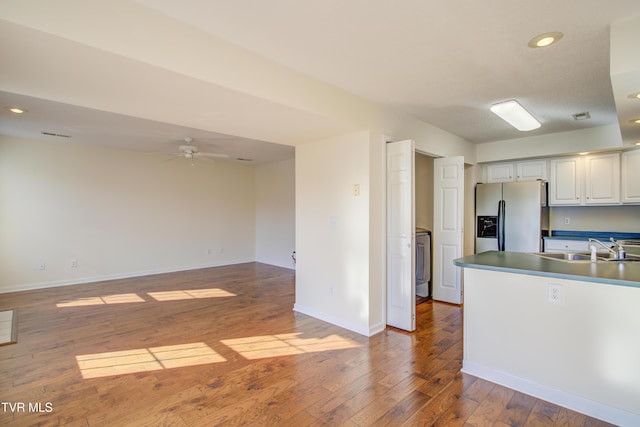 kitchen featuring white cabinetry, sink, washer / clothes dryer, stainless steel fridge, and hardwood / wood-style flooring