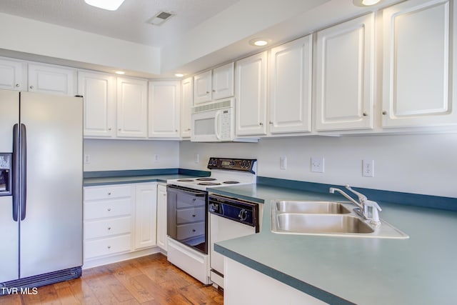 kitchen with white cabinets, white appliances, light hardwood / wood-style flooring, and sink