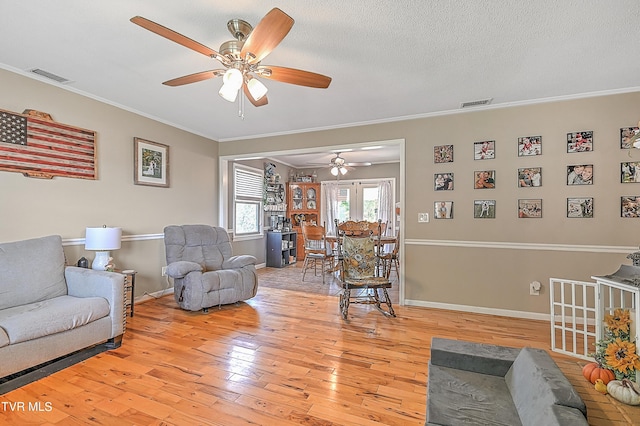 living room with crown molding, light hardwood / wood-style flooring, ceiling fan, and a textured ceiling