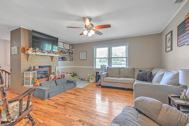 living room featuring crown molding, light hardwood / wood-style floors, a textured ceiling, and a brick fireplace