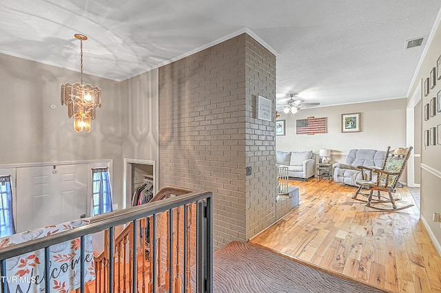 hall featuring hardwood / wood-style flooring, a notable chandelier, crown molding, and a textured ceiling