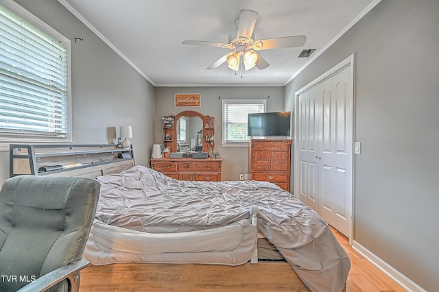 bedroom featuring light wood-type flooring, a closet, crown molding, and ceiling fan