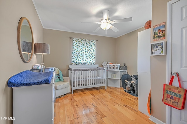 bedroom featuring hardwood / wood-style floors, ceiling fan, ornamental molding, and a textured ceiling