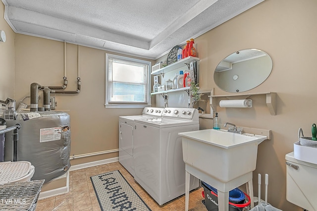 clothes washing area with sink, washing machine and dryer, light tile patterned floors, and a textured ceiling