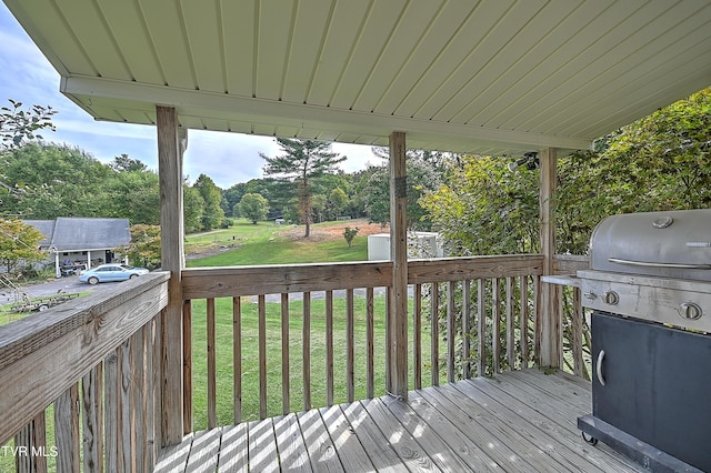 wooden deck featuring a lawn and a grill