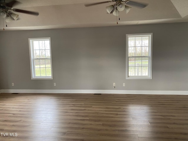 empty room featuring dark hardwood / wood-style floors, a wealth of natural light, and ceiling fan