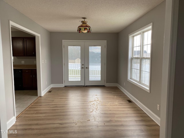 entryway featuring light hardwood / wood-style flooring, a textured ceiling, and french doors