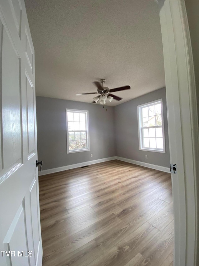 unfurnished room featuring ceiling fan, light hardwood / wood-style flooring, and a textured ceiling