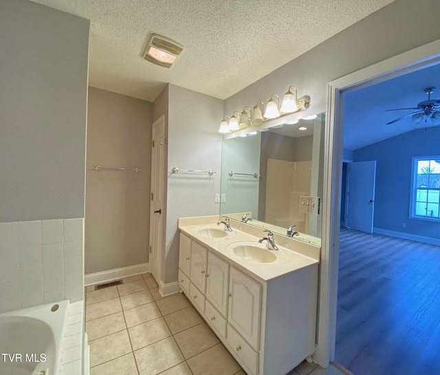 bathroom featuring ceiling fan, tile patterned floors, a textured ceiling, a bathtub, and vanity