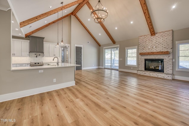 kitchen featuring decorative light fixtures, electric stove, tasteful backsplash, a fireplace, and high vaulted ceiling