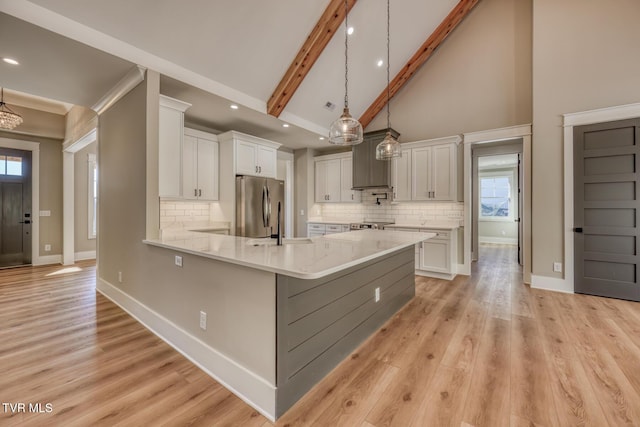 kitchen with tasteful backsplash, white cabinets, stainless steel refrigerator, and decorative light fixtures