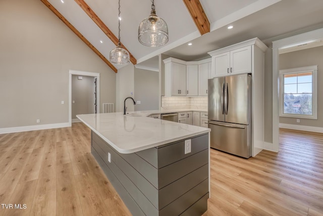 kitchen with white cabinets, appliances with stainless steel finishes, decorative light fixtures, beamed ceiling, and light stone counters