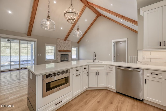 kitchen with white cabinetry, appliances with stainless steel finishes, backsplash, and decorative light fixtures