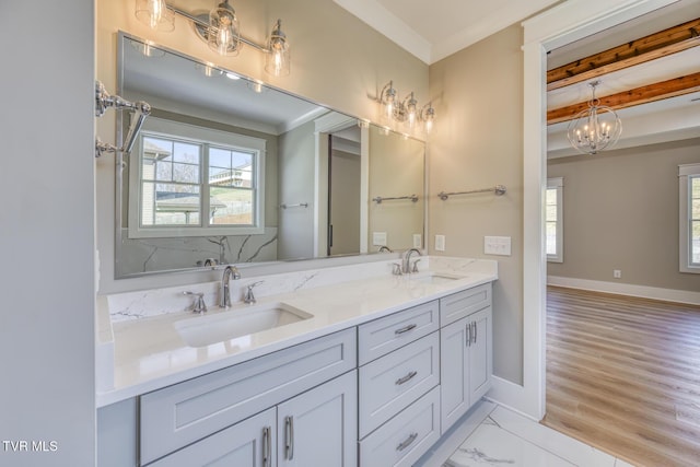 bathroom featuring wood-type flooring, vanity, ornamental molding, and a notable chandelier